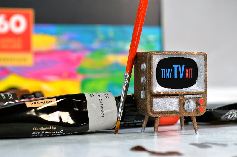 Pianted TinyTV Kit with Red Brush leaning on it and paint tubes behind it