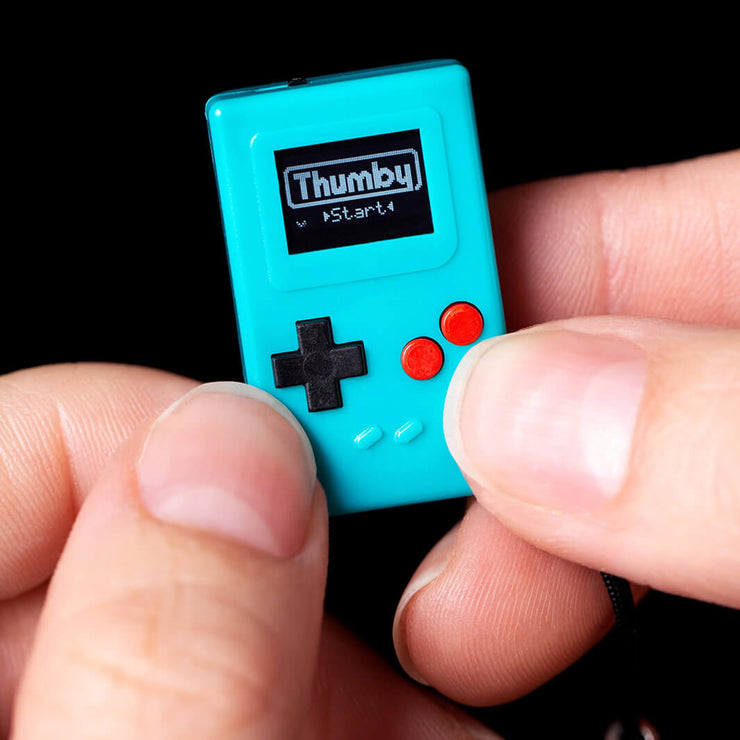Teal thumby held in fingertips of hands by TinyCircuits - tiniest game console